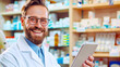 Smiling male pharmacist with tablet in a pharmacy, healthcare concept