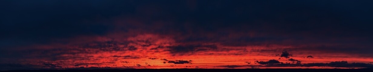 Fototapeta  ideal for sky replacement projects: panoramic aerial shot of a bloody red  illuminated clouds of dark  evening sky just after sunset.