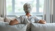 © AdriFerrer - Elderly woman sitting on couch, seen from behind, looking out window.