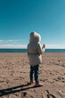 Playa Andalucía, niña con chaquetón en la arena tomando un helado