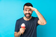 Young man with a cornet ice cream over isolated blue background looking far away with hand to look something