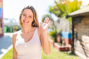 Young pretty woman at outdoors saluting with hand with happy expression