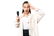 Young singer woman picking up a microphone over isolated chroma key background with surprise expression