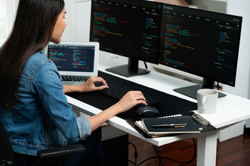 Young Asian in IT developer creating with typing online information on pc with coding program data of website application, wearing jeans shirt. surrounded by safety analysis two screens. Stratagem.