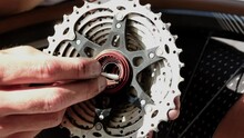 Close up video of male bicycle mechanic is repairing of bike wheel. Bicycle repair. Master cleans and lubricates the sprocket on the bicycle wheel. 