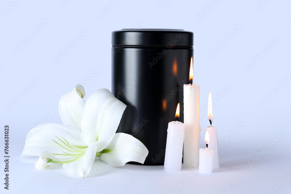 Mortuary urn, burning candles and beautiful lily flower on grey background