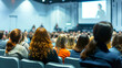 © Doraway - Image from behind of an audience member watching a person giving a speech on stage in a large venue.