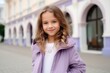 Portrait of a beautiful little girl in a purple jacket on the street