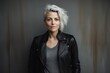 Portrait of a beautiful woman in a black leather jacket on a gray background