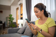 Asian woman sitting on sofa and holding credit card for online shopping by laptop and smart phone at home.
