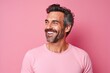 Portrait of a handsome middle-aged man smiling against pink background