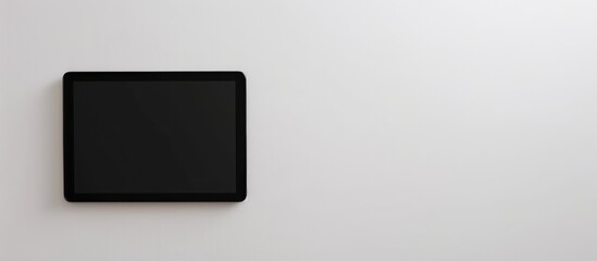 Wall Mural - A black tablet is placed alone against a white backdrop, with a blank screen providing space for text.