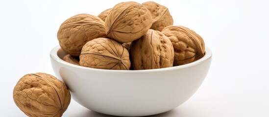 Canvas Print - A white bowl filled with walnuts, a versatile ingredient used in various recipes, sits on a clean white tableware background, ready for use in baked goods or as a staple food in cuisine dishes