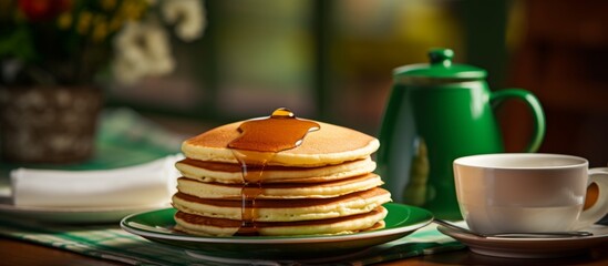 Poster - A stack of pancakes drizzled with syrup on a plate beside a cup of coffee, showcasing a delicious breakfast spread of baked goods and hot beverage on serveware