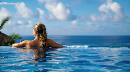 Wall Mural - A beautiful young woman in a pool with a stunning mesmerizing ocean view