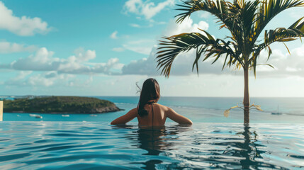 Wall Mural - A beautiful young woman in a pool with a stunning mesmerizing ocean view