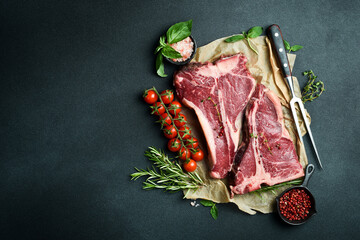 Wall Mural - Dry-aged Raw T-bone or porterhouse beef steak with herbs and salt. On a black stone background. Barbecue.