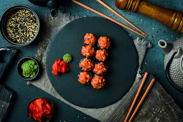 Wall Mural - Appetizing black sushi rolls with fish served on black board. Sushi set on a table.