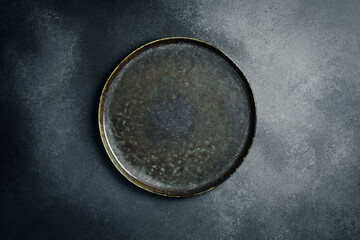 Wall Mural - Top view of dark stone plate on black background. Creative advertising photo. Free space for text.