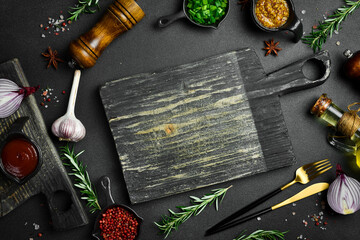Sticker - Kitchen cutting board on table with spices, vegetables and herbs. Free space for a recipe. Rustic style. On a dark background.