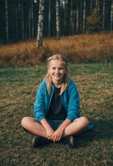 Wall Mural - A young girl is sitting in a field