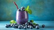 Blueberry smoothie with fresh berries and mint leaves on blue background