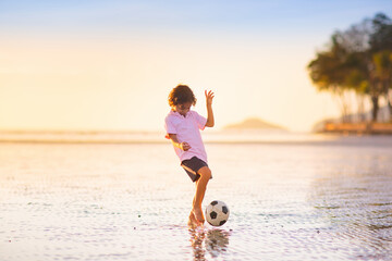 Wall Mural - Kids play football on tropical beach at sunset