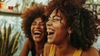 A joyful African American woman with curly hair laughs loudly while listening to a funny story from