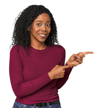 African American woman in studio setting shocked pointing with index fingers to a copy space.