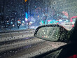 Melted snow and sleet drops on the car window with view to the side mirror. Winter night urban scene