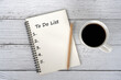 Cup of coffee and To do list text on notepad