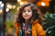 Portrait of cute little girl with curly hair in yellow jacket.
