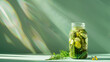 mason jar with pickles and herbs on pastel green background with copy space, sun rays, soft shadows
