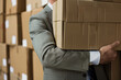 Businessman exerting effort to move a stack of cardboard boxes
