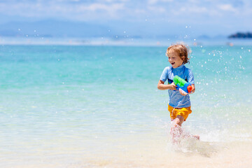 Poster - Child with toy water gun. Kids vacation beach fun.