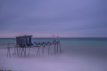 Wall Mural - wooden fishing piers lying on the sea of Marmara cloudy weather sunset hours while the waves hit the beach