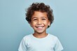Cheerful little boy looking at camera with toothy smile, over blue background