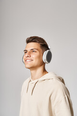 Wall Mural - smiling young man with brown hair in headphones looking to up on light background