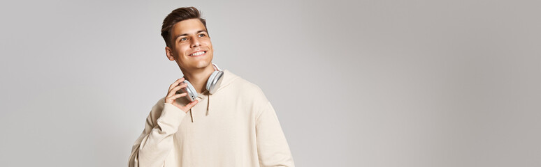 Wall Mural - banner of attractive young man in headphones with skateboard looking to up on light background