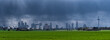 Extremes Unwetter mit Starkregen zieht die Skyline von Frankfurt am Main am Horizont mit einem grünen Feld im Vordergrund