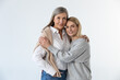 Mother and daughter standing together on a white background