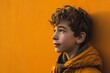 Portrait of a boy in a yellow jacket against the orange wall