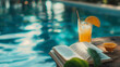 An open book and a orange juice are placed on a wooden table next to a pool in blurred background with a relaxed ambience. Background for relaxation, vacation and rest time.