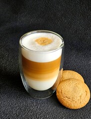 Wall Mural - A glass of delicious latte and cookies on a black background. Delicious latte macchiato and cookies. Close-up