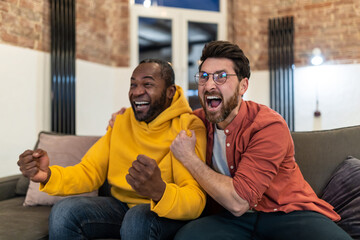 Wall Mural - Two friends watching tv and looking excited and emotional