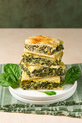 Poster - Stack of Spanakopita piece of Greek savory pie, homemade. With  spinach, cheese feta, chopped spinach, green, egg, layered in phyllo or filo dought. Vertical image.