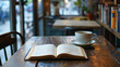 An open book and a coffee cup are placed on a wooden table inside a cafe on a blurred dusk background with a relaxed ambience. Background for relaxation, vacation and rest time.