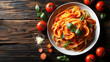 Top view of a bowl of spaghetti with tomato sauce, garnished with basil, surrounded by tomatoes and grated cheese on a wooden table.