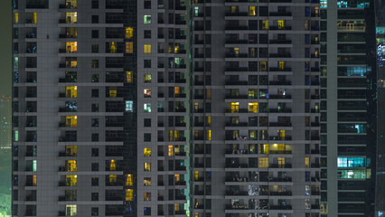 Wall Mural - Windows of the multi-storey building of glass and steel lighting inside and moving people within timelapse