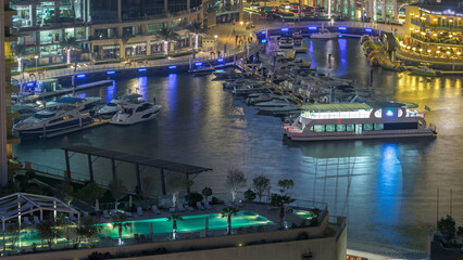 Wall Mural - Promenade and canal in Dubai Marina with luxury skyscrapers and yachts around night timelapse, United Arab Emirates